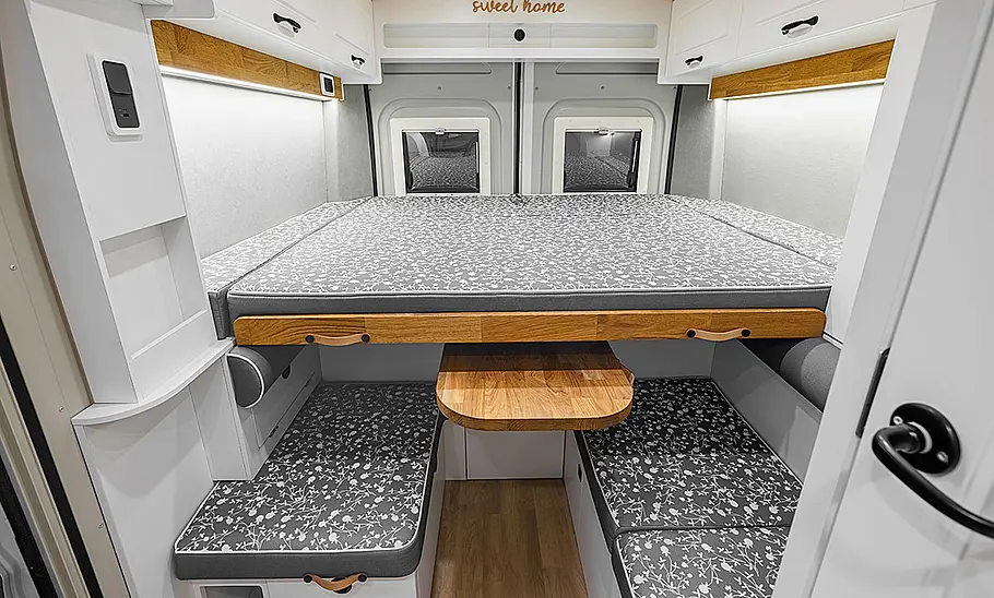 Das Bild zeigt den Wohnraum des Freedo RV 541 HT (2025) mit vollständig aufgebautem Heckbett und Blick in Richtung Fahrzeugheck.