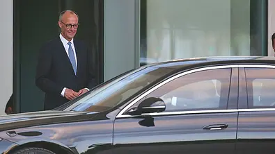 Friedrich Merz steht hinter seinem ausschnittsweise zu sehenden Kanzlerauto Mercedes S 680 Guard. - Foto: Imago