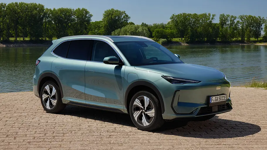 Der Geely E5 steht an einem Gewässer, von vorne rechts fotografiert.