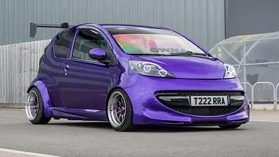 Der Peugeot 107 mit Widebody-Kit steht auf einem Platz und wurde von schräg vorne fotografiert. - Foto: Instagram / tarawiththe107