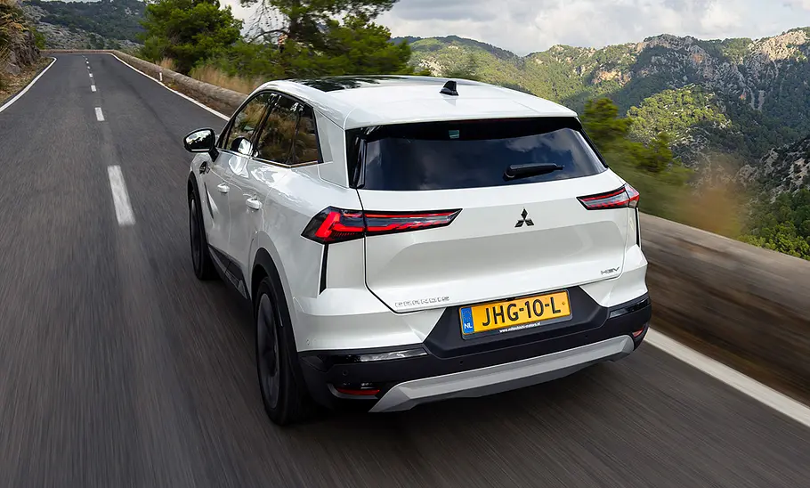 Der Mitsubishi Grandis (2025) fährt auf einer Straße, fotografiert von hinten schräg.