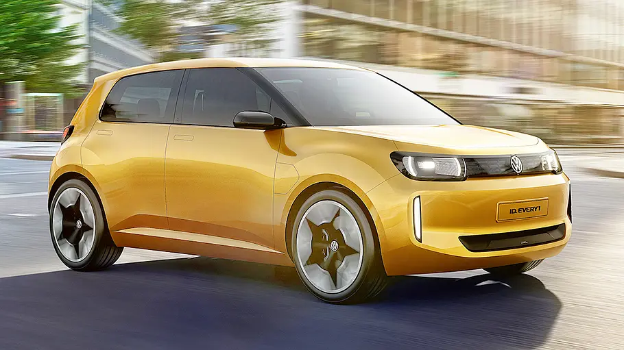 VW ID.1 Ein gelber VW ID. Every1 fährt durch eine Stadt, Ansicht von der rechten Seite.