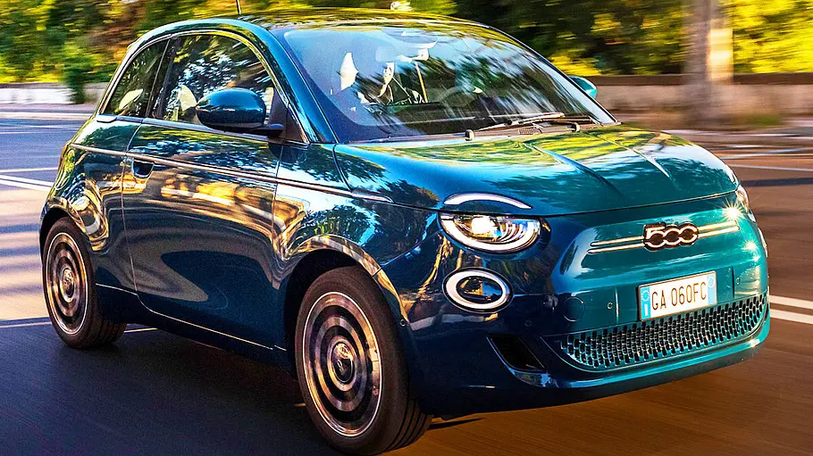 Der Fiat 500 Elektro fährt auf einer Straße, von vorne rechts fotografiert.