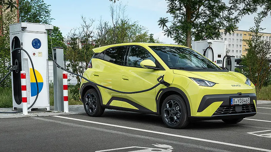 Der BYD Dolphin Surf steht angesteckt an einer Ladesäule, von vorne rechts fotografiert.