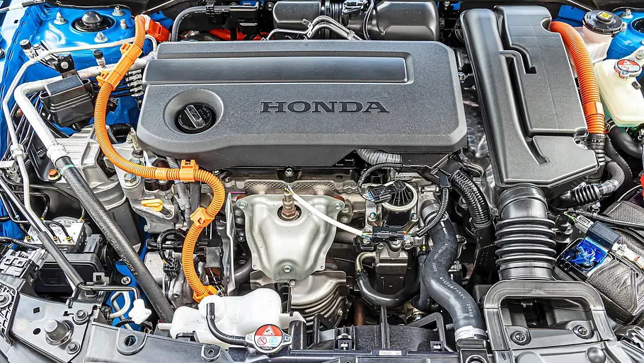 BMW 2er Coupé gegen Honda Prelude im Vergleichstest Der Motorraum eines blauen Honda Prelude zeigt eine schwarze Motorabdeckung, orange Kabel, Schläuche und Flüssigkeitsbehälter.