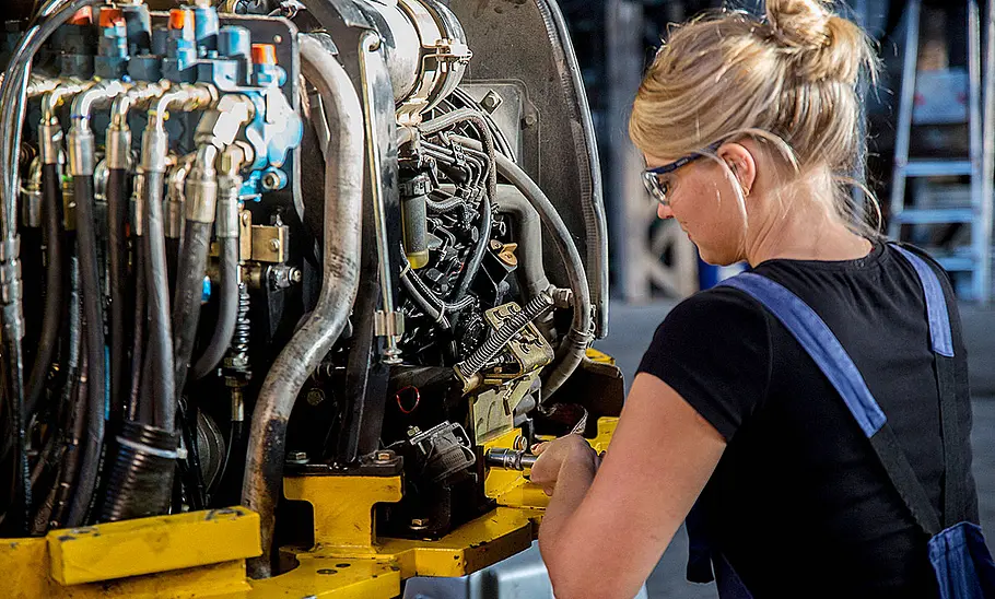 Eine Mechanikerin wartet das hydraulische System einer Baumaschine.