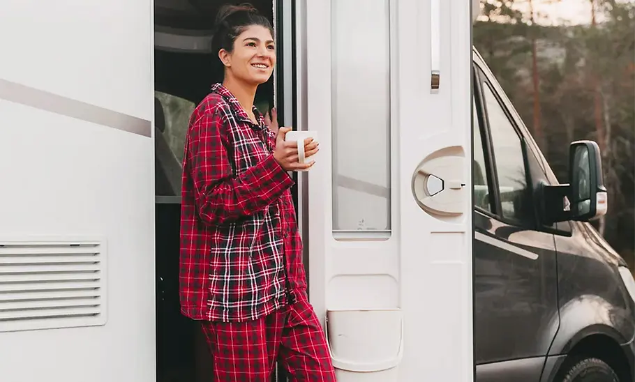 Die Außenaufnahme zeigt eine Frau im Pyjama, die die Hymer B-Klasse Modern Comfort T 600 (2025) durch die Aubautüre verlässt-