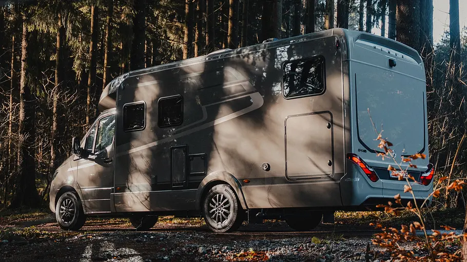 Der Hymer GT-S 685 von schräg hinten links auf einem Waldweg im Halbschatten stehend.