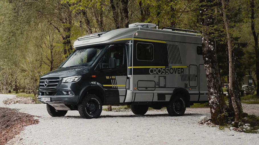 Der Hymer ML-T CrossOver statisch von schräg vorne links auf einer Steinbank an einem Bachufer.