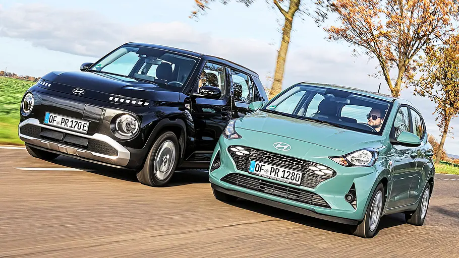Blick von schräg vorne auf die beiden Kleinwagen Hyundai Inster und Hyundai i10, die nebeneinander herfahren.