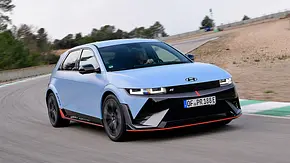 Hyundai Ioniq 5 N fährt auf einer Rennstrecke eine Linkskurve. Ansicht von vorne rechts. - Foto: Hyundai