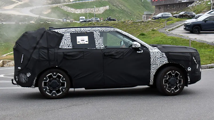 Hyundai Tucson (2027) Der Erlkönig des Hyundai Tucson (2027) fahrend auf einem Alpenpass von der Seite rechts.