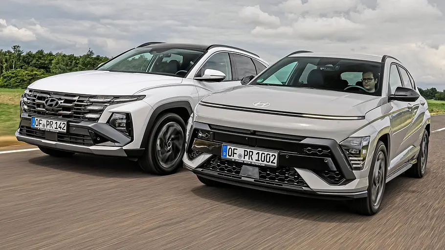 Hyundai Tucson und Hyundai Kona Hyundai Tucson und Hyundai Kona fahren nebeneinander auf einer Landstraße, Ansicht von vorne.