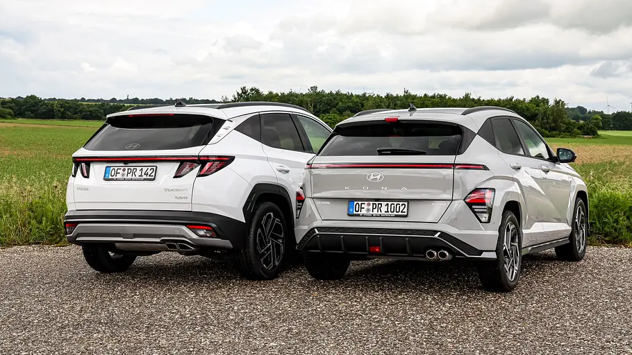 Hyundai Tucson und Hyundai Kona Hyundai Tucson und Hyundai Kona stehen auf einem asphaltierten Platz, Ansicht von hinten.