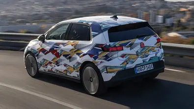 Der VW ID. Polo fährt durch eine Linkskurve, fotografiert von schräg hinten. - Foto: VW