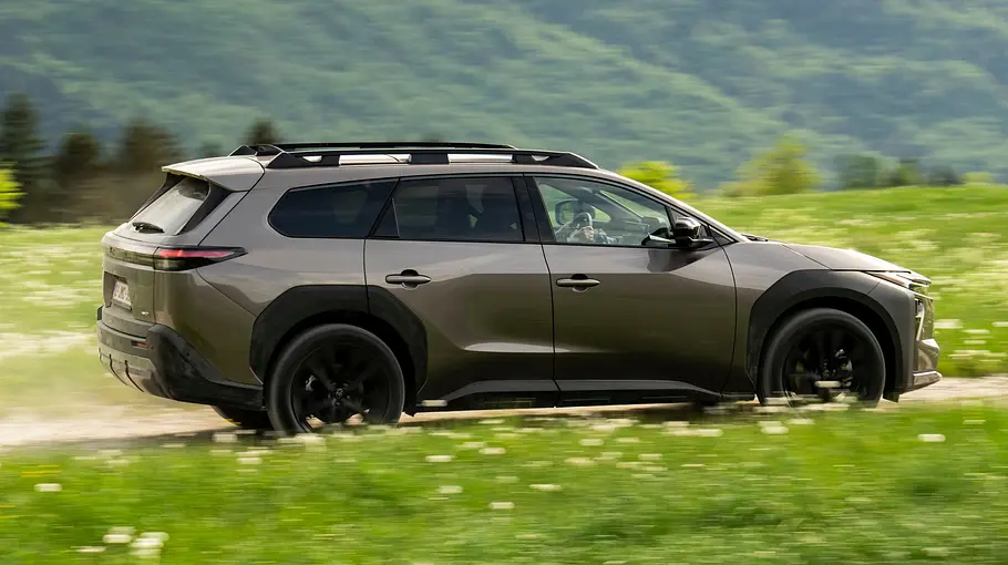 Toyota bZ4X Touring AWD auf einer Schotterpiste fahrend von der Seite.