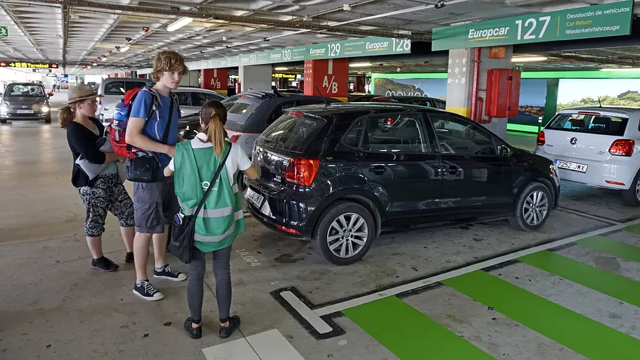 Mietwagen Versicherung Menschen stehen hinter einem Auto und machen eine Übergabe.