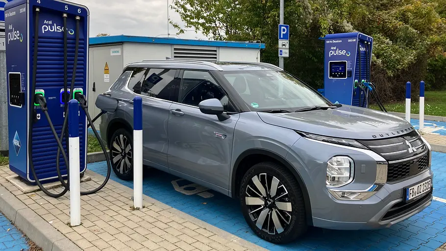 Der Mitsubishi Outlander steht an einer Ladesäule, fotografiert von schräg vorne.