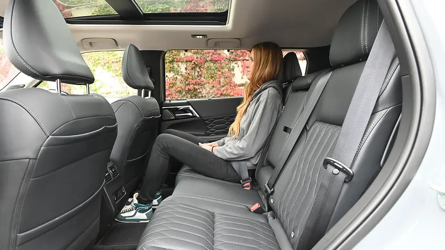 Die Rücksitzbank des Mitsubishi Outlander, darauf sitzt eine junge Frau, von der Seite fotografiert..