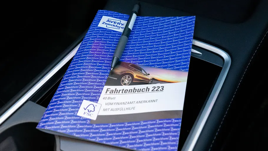 Fahrtenbuch führen Fahrtenbuch mit Stift auf der Mittelkonsole, fotografiert im Auto.