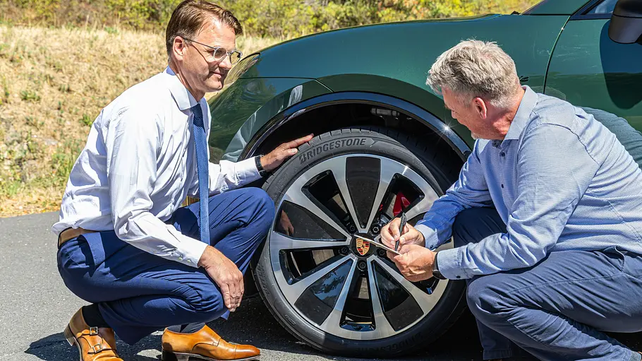 Christian Mühlhäuser im Interview mit AUTO ZEITUNG-Redakteur Martin Urbanke. Christian Mühlhäuser (li.) kniet beim Interview mit AUTO ZEITUNG-Redakteur Martin Urbanke vor einem Bridgestone Reifen, der an einem Porsche montiert ist.