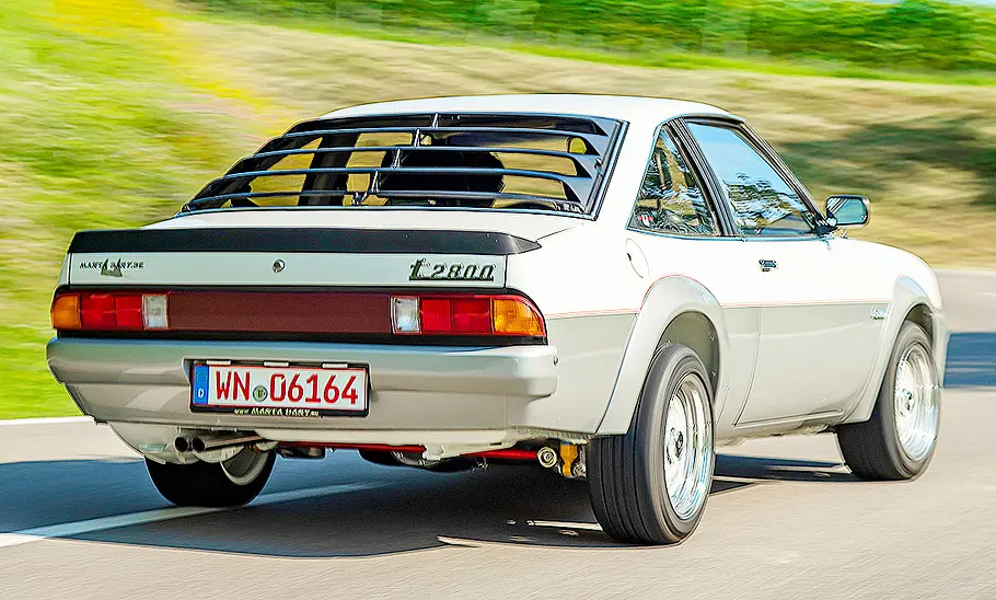 Der Irmscher i2800 fährt auf der Landstraße durch eine Kurve, fotografiert von schräg hinten.