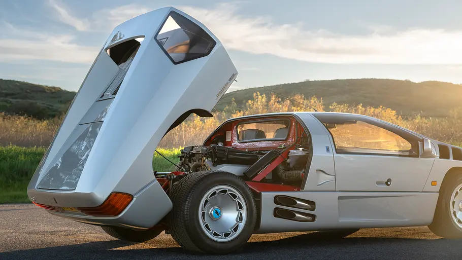Der Isdera Imperator 108i stehend von schräg hinten mit geöffneter Motorhaube.