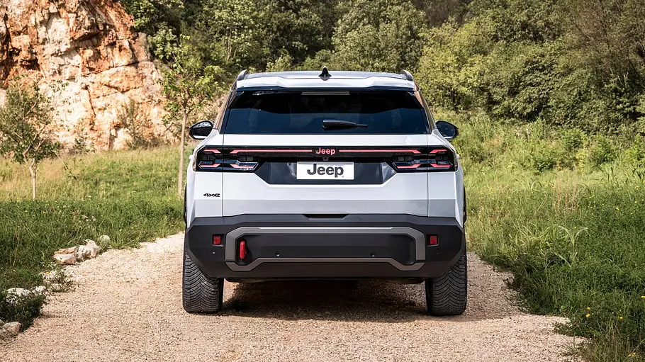 Der Jeep Compass 4xe Elektro steht im Gelände, von hinten fotografiert.