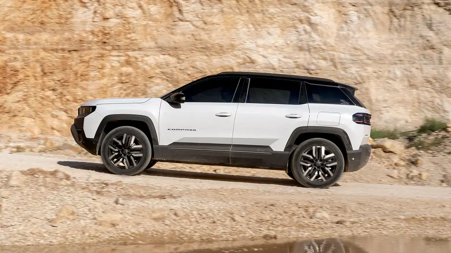 Der Jeep Compass 4xe Elektro fährt durchs Gelände, von links fotografiert.