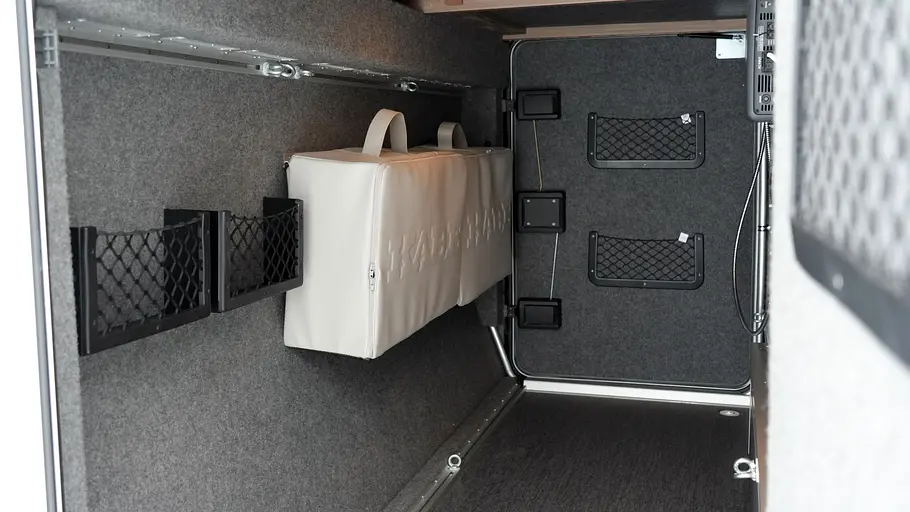 Blick durch die rechte Garagentüre in die Heckgarage des Kabe Novum Traq 750 in der zwei Taschen aus dem Zubehör der Marke an der Heckwand befestigt sind.