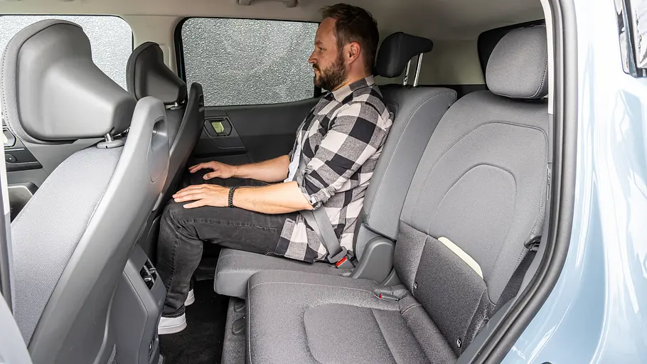 Kia EV2 Einzeltest Eine Person auf den Rücksitzen des Kia EV2 durch die geöffnete Hintertüre fotografiert. Der rechte Rücksitz ist nach vorne geschoben.