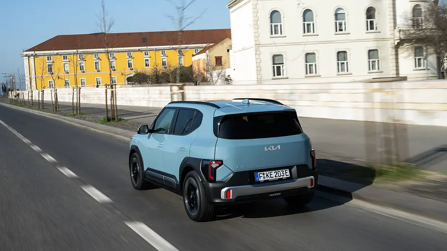 Der Kia EV2 fahrend auf einer Straße von hinten.