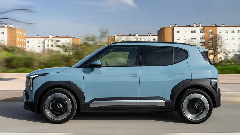 Der Kia EV2 fahrend auf einer Straße in der Seitenansicht.