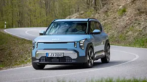 Der Kia EV2 durch eine leichte Rechtskurve auf einer Landstraße fahrend von schräg vorne links. - Foto: Kia Der Kia EV2 durch eine leichte Rechtskurve auf einer Landstraße fahrend von schräg vorne links. - Foto: Kia