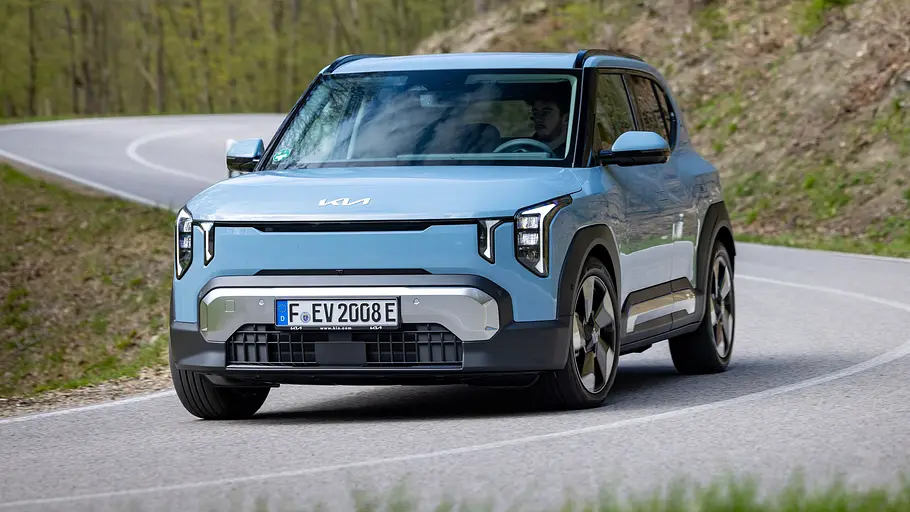 Kia EV2 Leasing-News Der Kia EV2 durch eine leichte Rechtskurve auf einer Landstraße fahrend von schräg vorne links.
