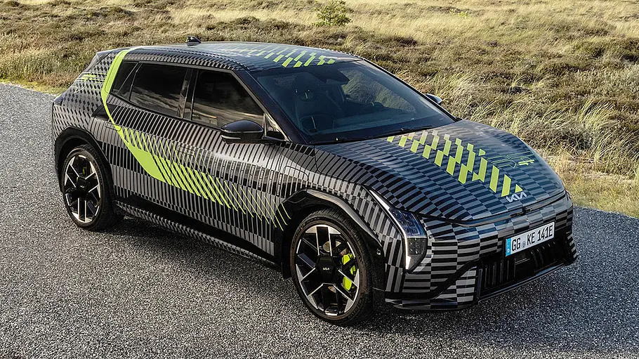 Der Kia EV4 GT steht mit bunter Folierung auf einer Straße, von vorne rechts fotografiert.