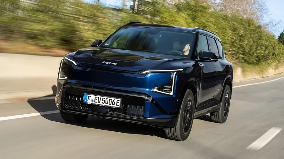 Der Kia EV5 fährt auf einer Straße, von vorne links fotografiert.