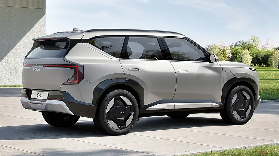 Der Kia EV5 (2025) steht in einer Einfahrt, von hinten rechts fotografiert.