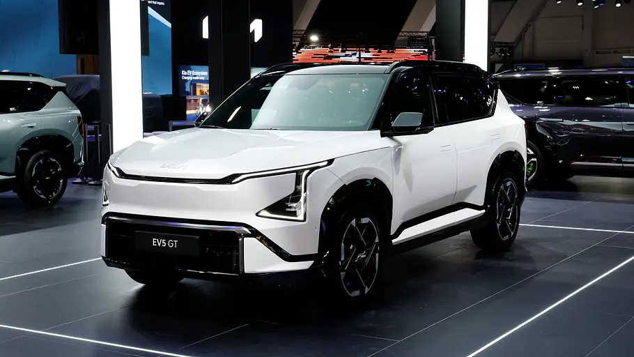 Der Kia EV5 GT steht auf einer Messe, von vorne links fotografiert.