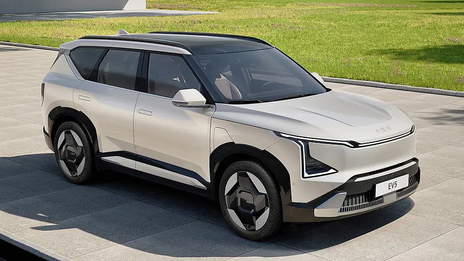 Der Kia EV5 (2025) steht in einer Einfahrt, von vorne rechts fotografiert.