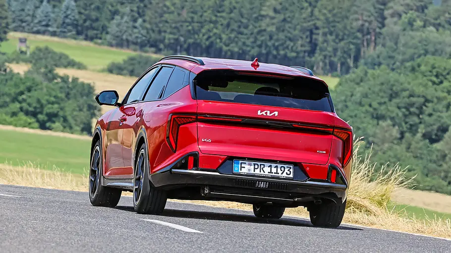Der Kia K4 Sportswagon durch eine Linkskurve fahrend von schräg hinten links fotografiert.