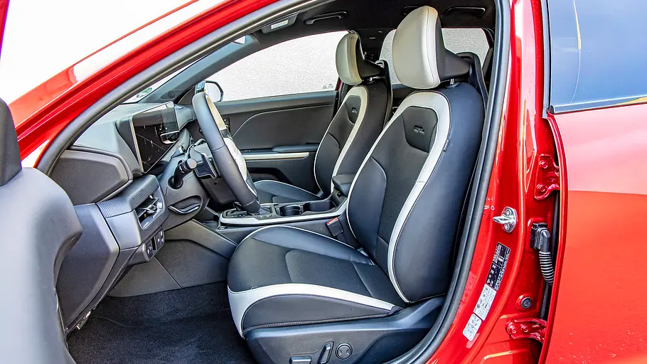 Blick durch die geöffnete Fahrertüre auf die Vordersitze im Kia K4 Sportswagon.