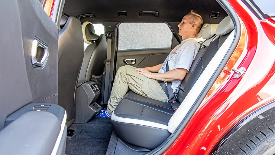 Blick durch die geöffnete linke Hintertüre auf die Rückbank des Kia K4 Sportswagon, auf der eine Person sitzt.