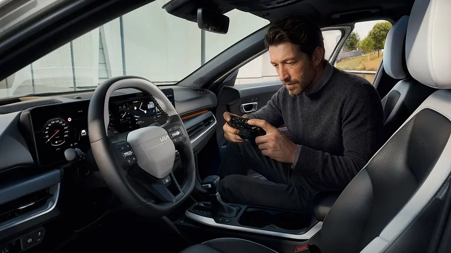 Kia K4 Sportswagon Firmenwagen Blick durch die Fahrertüre ins Cockpit des Kia K4 Sportswagon. Eine Person sitzt auf dem Beifahrersitz und bedient ein Smartphone.