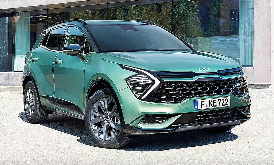 Kia Sportage steht vor einer gläsernen Hausfront, Ansicht von vorne rechts.