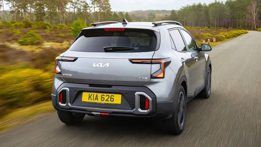 Kia Stonic Facelift Kia Stonic (2026) fährt auf einer Landstraße, Ansicht von hinten.
