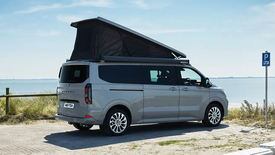 Der Ford Nugget mit langem Radstand statisch von schräg hinten rechts mit geöffnetem Aufstelldach.