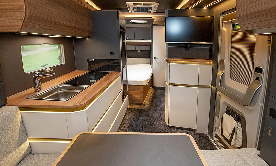 Knaus Azur 500 FU (2022) Wohnraum: von der Sitzecke aus gesehen mit Blick durch den Wohnwagen, Küchenzeile links, Eingangstür rechts