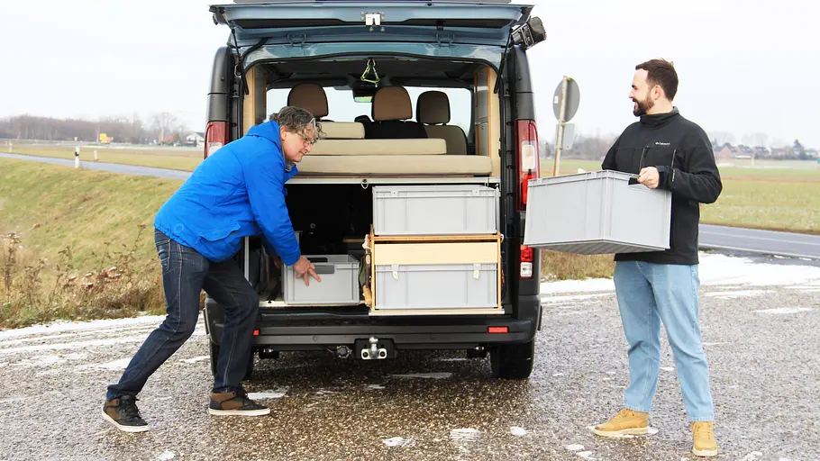 Kompanja Eins Zwei Personen laden Euroboxen in die Heckgarage des Kompanja Eins.