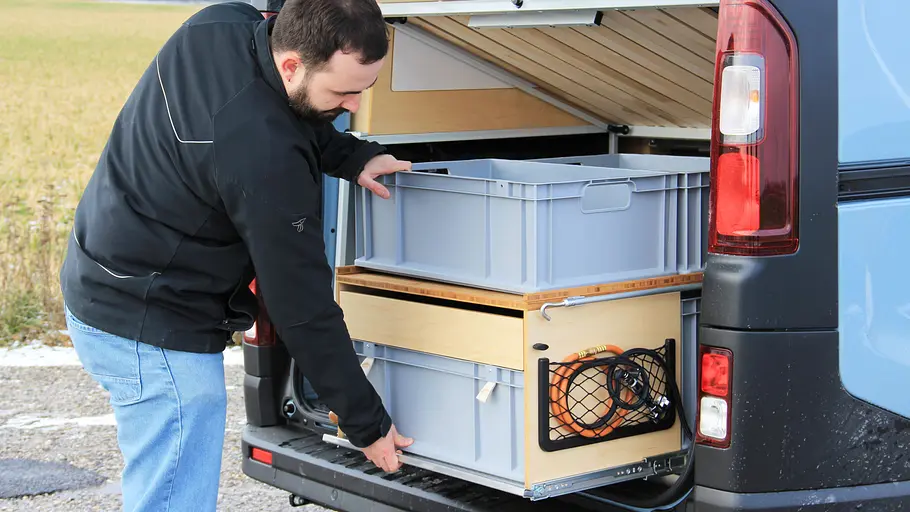 Ein Testredakteur zieht das Küchenmodul aus dem Heck.